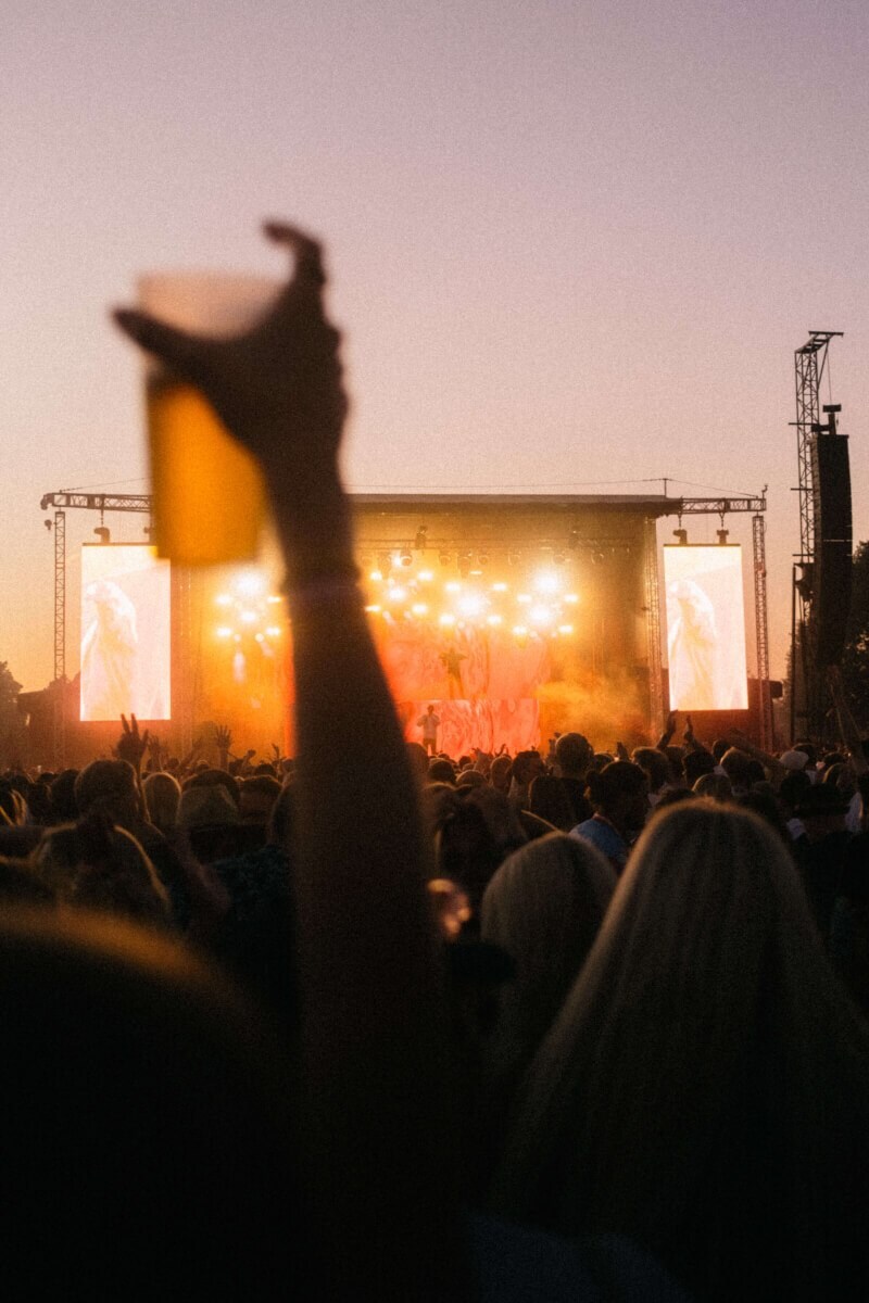 Øl og god musik foran scenen, mens solen går ned over menneskemængden til AiaSound-festivalen.