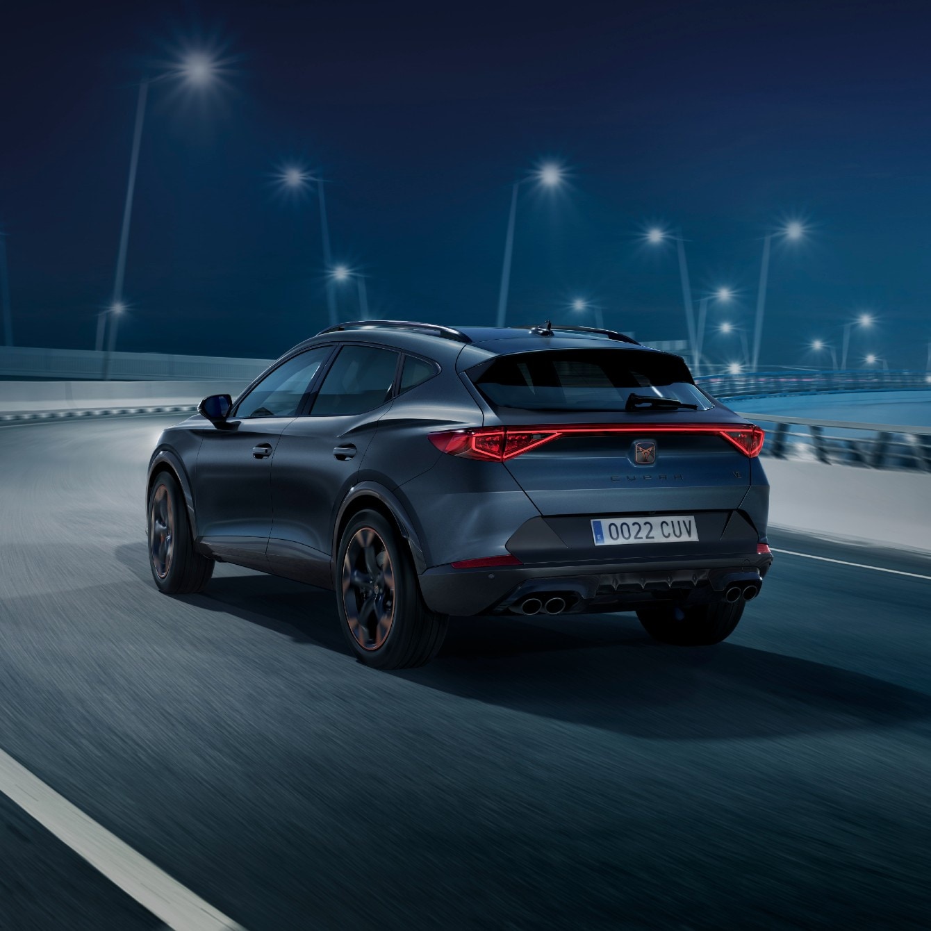 CUPRA Tavascan VZ in blue charging with CUPRA Charger, parked in a modern garage with purple ambient lighting.