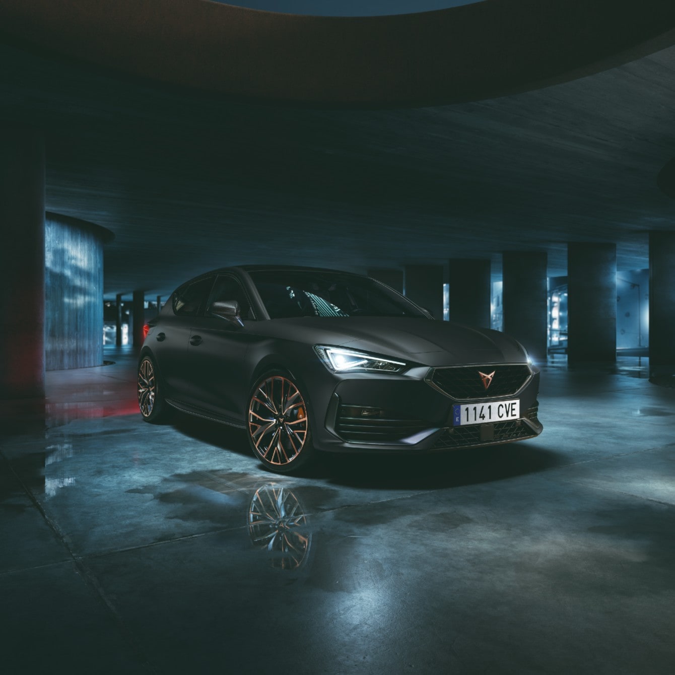 CUPRA Tavascan VZ in blue charging with CUPRA Charger, parked in a modern garage with purple ambient lighting.