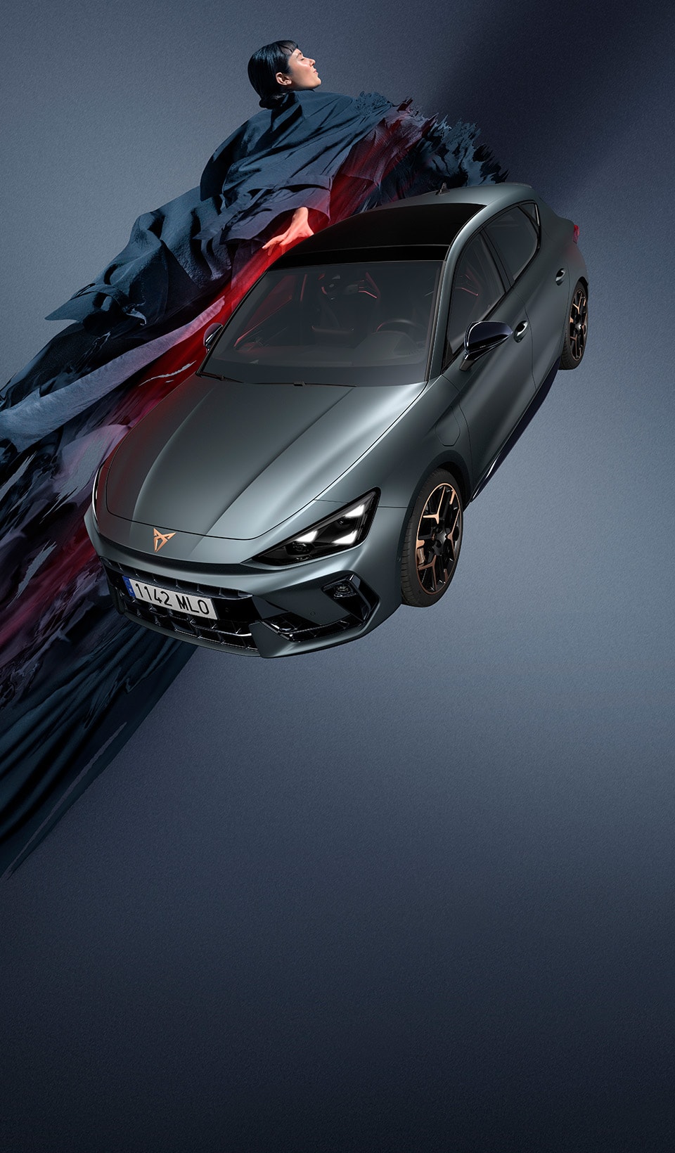 A dynamic scene featuring a CUPRA car in a sleek dark metallic color, positioned beside a blurred figure of a woman in a white dress using a VR headset and holding a conductor’s baton. 