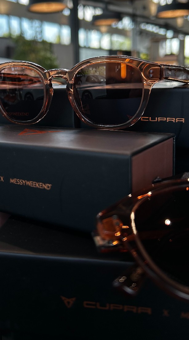 A minimalist image featuring a person wearing a dark hooded garment with subtle metallic details, against a black background.